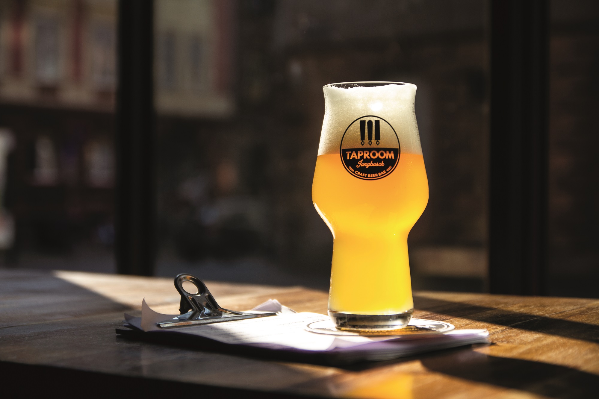 Glass of beer on drinks menu on table in basking in sunlight